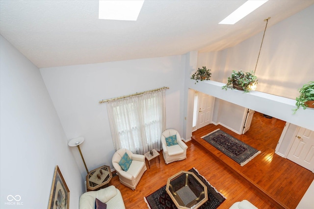 living room featuring vaulted ceiling with skylight and light hardwood / wood-style floors