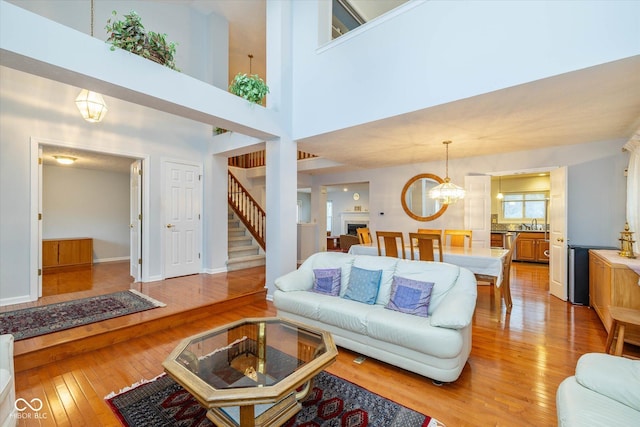 living room with sink, a chandelier, light hardwood / wood-style floors, and a towering ceiling