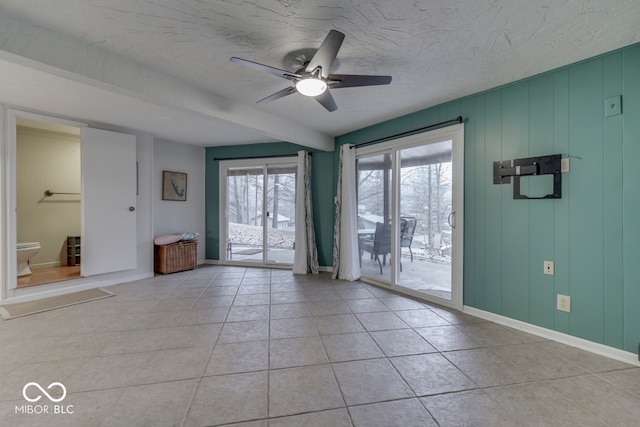 tiled empty room featuring ceiling fan and a textured ceiling