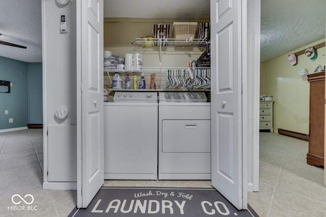 washroom featuring light tile patterned floors, washing machine and dryer, a textured ceiling, and a baseboard heating unit