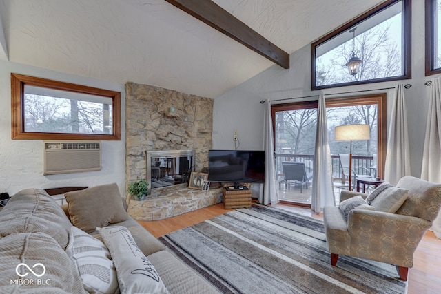 living room with hardwood / wood-style flooring, vaulted ceiling with beams, a wall unit AC, a fireplace, and a textured ceiling