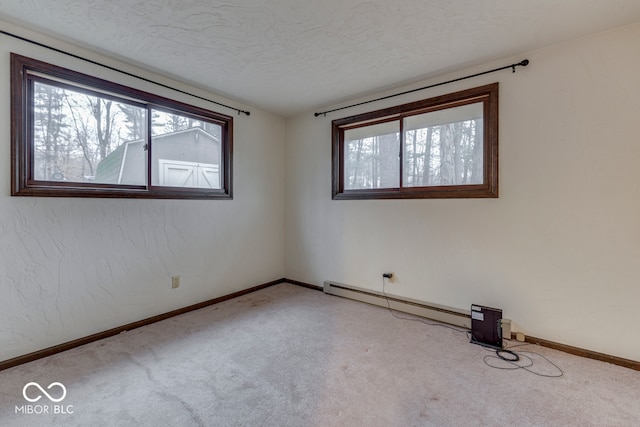 empty room with a baseboard heating unit, light colored carpet, and a textured ceiling