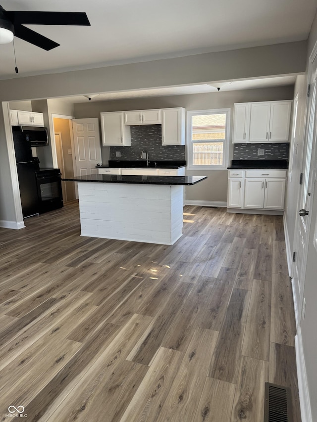 kitchen featuring backsplash, wood-type flooring, sink, and white cabinets