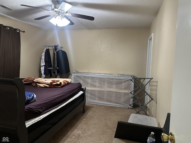 carpeted bedroom with ceiling fan and a textured ceiling