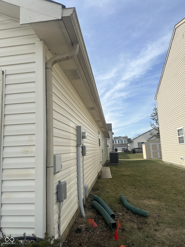 view of home's exterior featuring central AC unit, a lawn, and a storage unit