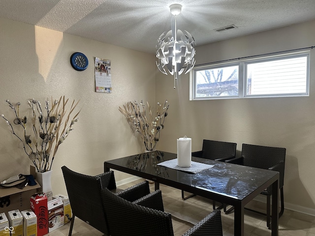 dining space with a textured ceiling and a notable chandelier