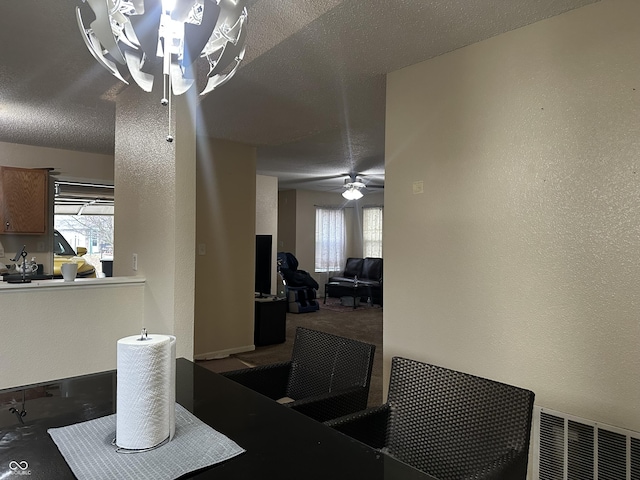 dining space with ceiling fan, carpet floors, and a textured ceiling