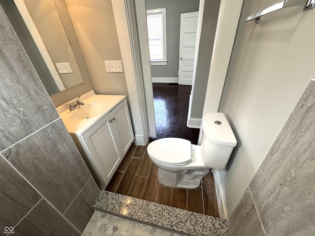 half bath with baseboards, vanity, toilet, and wood tiled floor