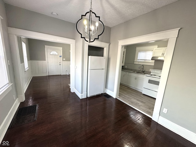 interior space with visible vents, an inviting chandelier, dark wood-type flooring, a sink, and a textured ceiling