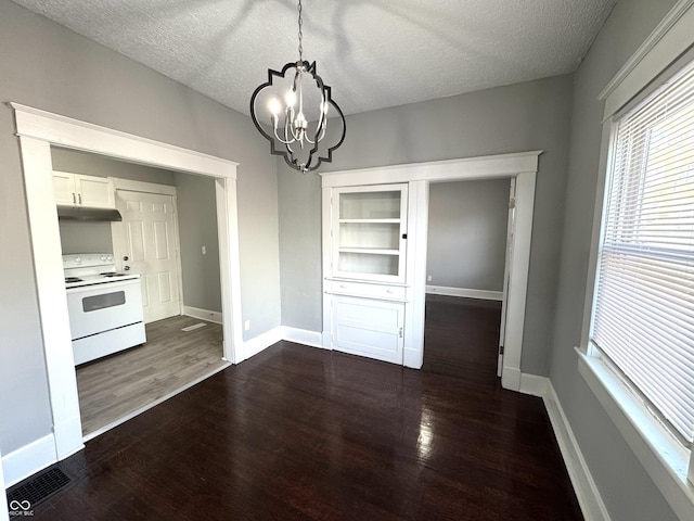 unfurnished dining area featuring a wealth of natural light, dark wood finished floors, and a textured ceiling