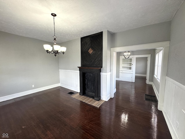 unfurnished living room featuring a chandelier, a textured ceiling, and wood finished floors