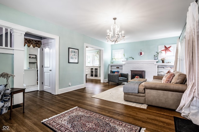 living room with dark hardwood / wood-style floors, a notable chandelier, and a fireplace