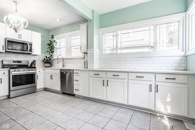 kitchen featuring white cabinetry, hanging light fixtures, decorative backsplash, and stainless steel appliances