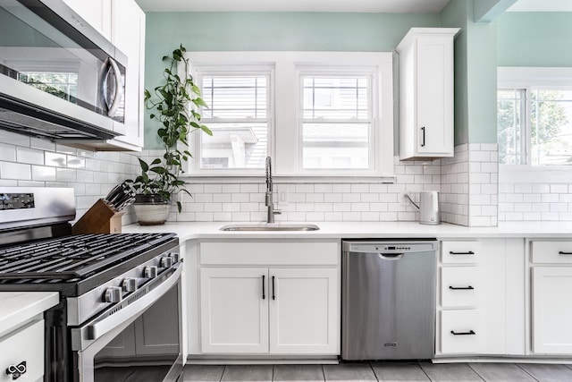 kitchen with sink, backsplash, stainless steel appliances, and white cabinets