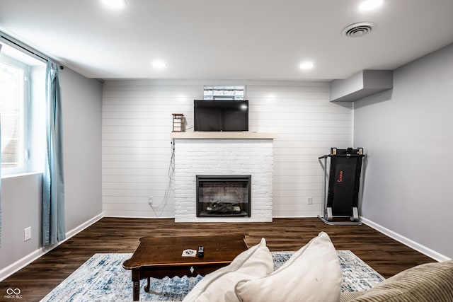 living room with a brick fireplace and dark hardwood / wood-style flooring