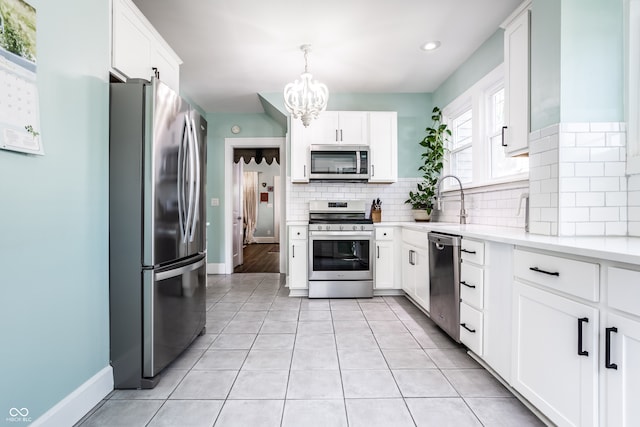 kitchen with tasteful backsplash, stainless steel appliances, hanging light fixtures, and white cabinets