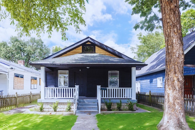 view of front of house featuring a front lawn, fence, a porch, and roof with shingles