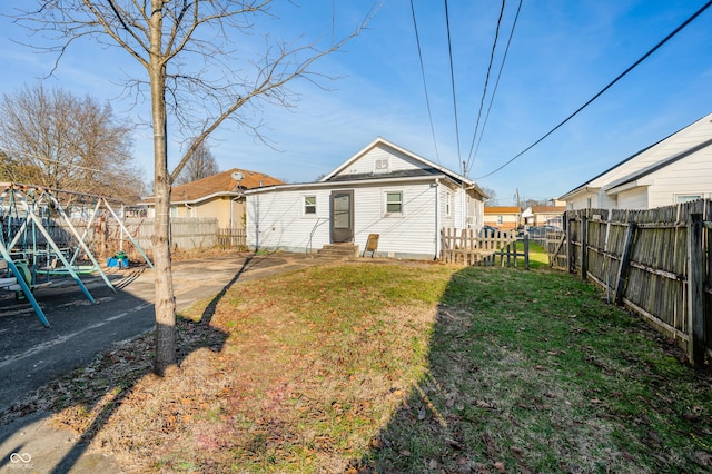 back of house with a lawn and a playground