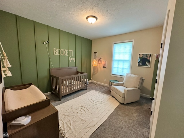 carpeted bedroom featuring a nursery area and a textured ceiling