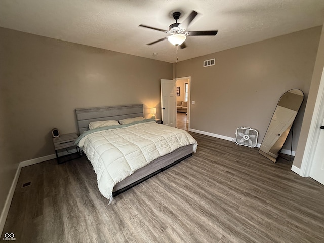 bedroom featuring dark hardwood / wood-style flooring, a textured ceiling, and ceiling fan