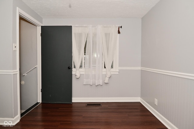 empty room with dark hardwood / wood-style floors and a textured ceiling