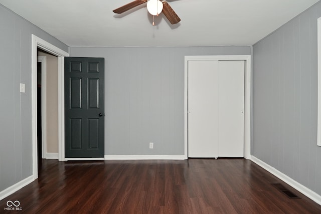 unfurnished bedroom with dark wood-type flooring, ceiling fan, and a closet