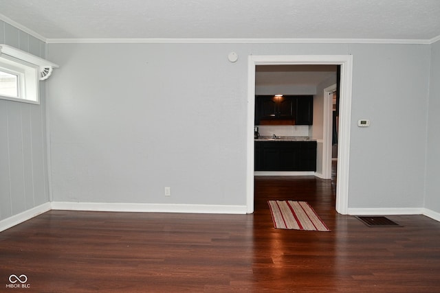 empty room with sink, crown molding, dark hardwood / wood-style floors, and a textured ceiling