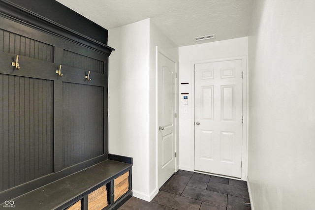 mudroom featuring dark tile patterned flooring and a textured ceiling