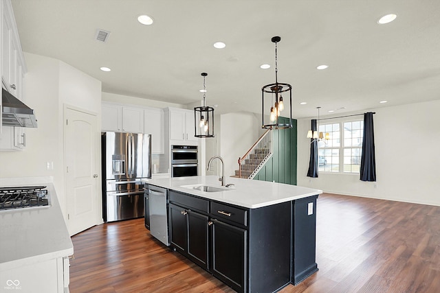 kitchen with sink, white cabinetry, hanging light fixtures, a center island with sink, and appliances with stainless steel finishes