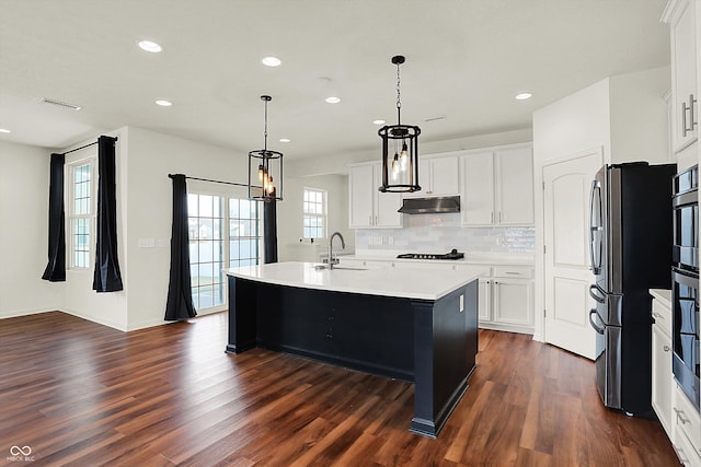 kitchen featuring an island with sink, sink, white cabinets, and decorative light fixtures