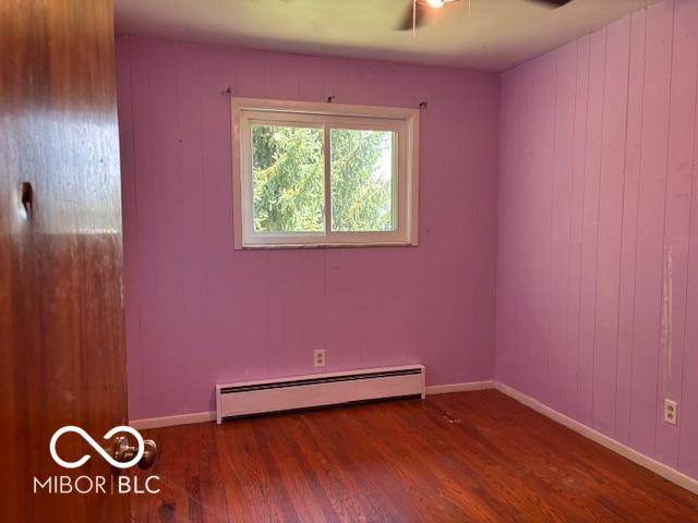 79 Circle Dr, Mooresville, IN 46158 - spare room featuring a baseboard heating unit, wood finished floors, and a ceiling fan