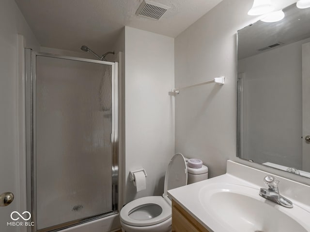 bathroom featuring a shower with door, vanity, and toilet