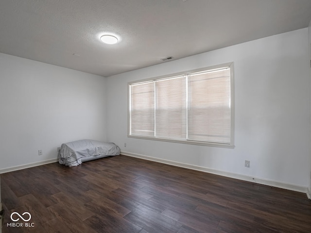 unfurnished bedroom with a textured ceiling and dark hardwood / wood-style flooring