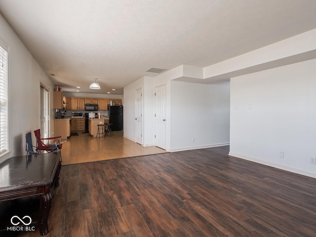 unfurnished living room featuring dark wood-type flooring and a textured ceiling