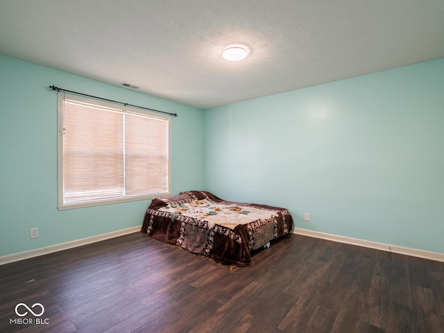 bedroom with dark hardwood / wood-style flooring and a textured ceiling