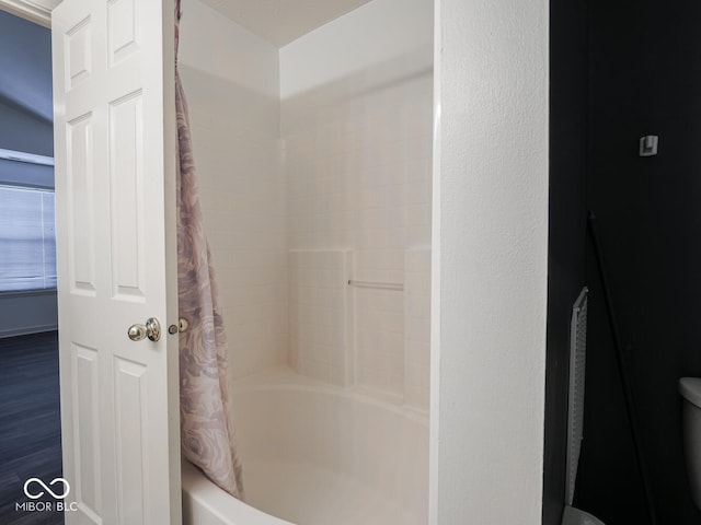 bathroom with shower / bathtub combination with curtain, hardwood / wood-style flooring, and toilet