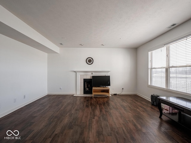 living room with a tile fireplace, dark wood-type flooring, and a textured ceiling