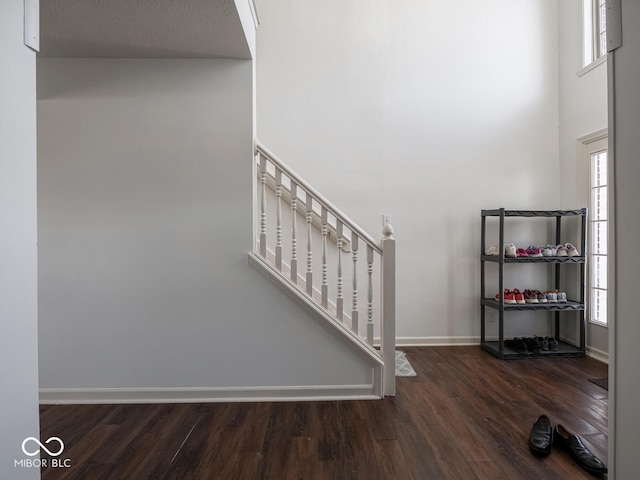 staircase with hardwood / wood-style flooring, a healthy amount of sunlight, and a high ceiling