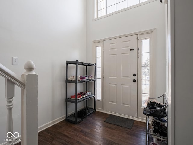 entryway with dark wood-type flooring and a towering ceiling