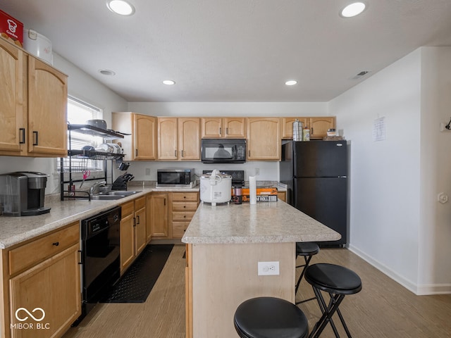 kitchen featuring sink, hardwood / wood-style floors, black appliances, a kitchen island, and light brown cabinetry