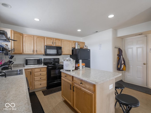 kitchen featuring a kitchen island, sink, light wood-type flooring, and black appliances