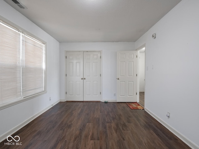 unfurnished bedroom featuring dark hardwood / wood-style floors and a closet