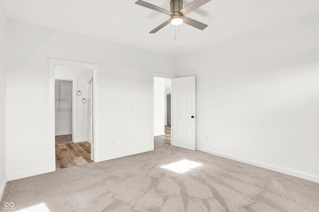 unfurnished bedroom featuring ceiling fan, light colored carpet, a closet, and a walk in closet