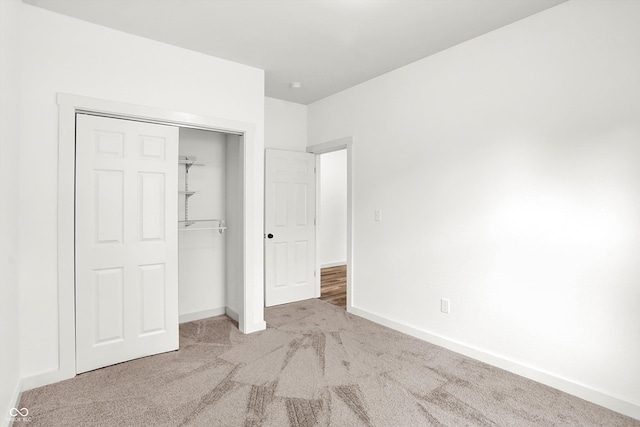 unfurnished bedroom with light carpet and a closet