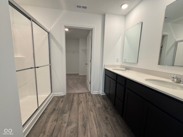 bathroom with hardwood / wood-style flooring, vanity, and an enclosed shower