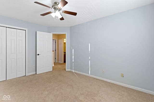 unfurnished bedroom with ceiling fan, a closet, light carpet, and a textured ceiling