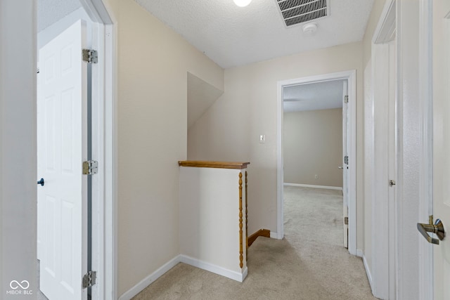 corridor featuring light colored carpet and a textured ceiling