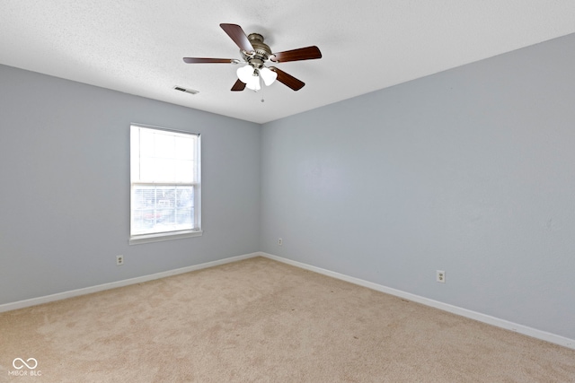 spare room with ceiling fan, light carpet, and a textured ceiling