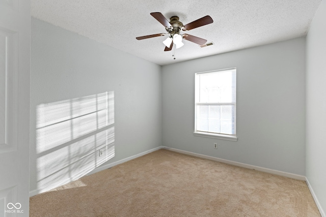 unfurnished room featuring ceiling fan, light colored carpet, and a textured ceiling