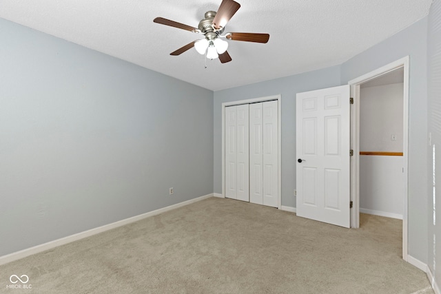 unfurnished bedroom with ceiling fan, light colored carpet, a closet, and a textured ceiling